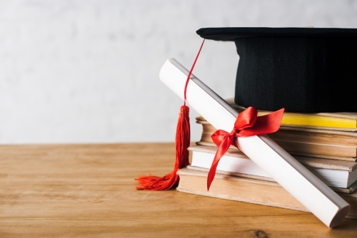 Graduation cap lying on books.